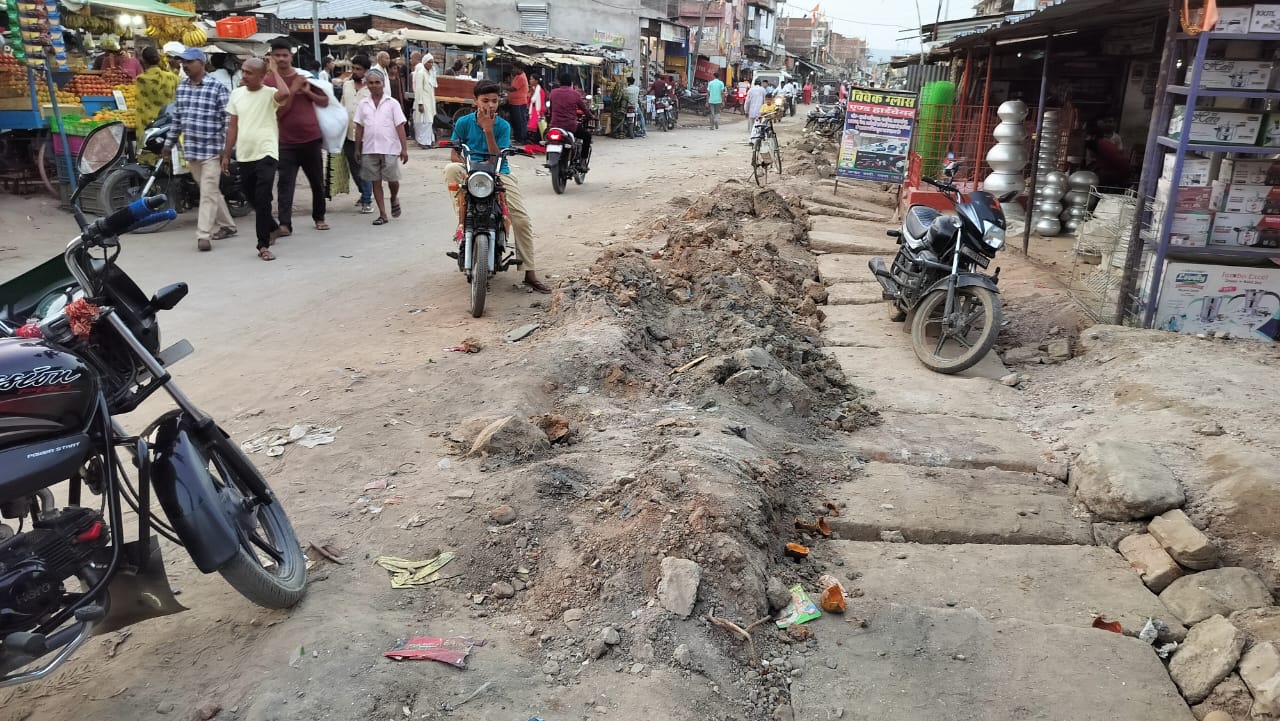 नाली सफाई के बाद सड़क पर फैला मिट्टी व पत्थर