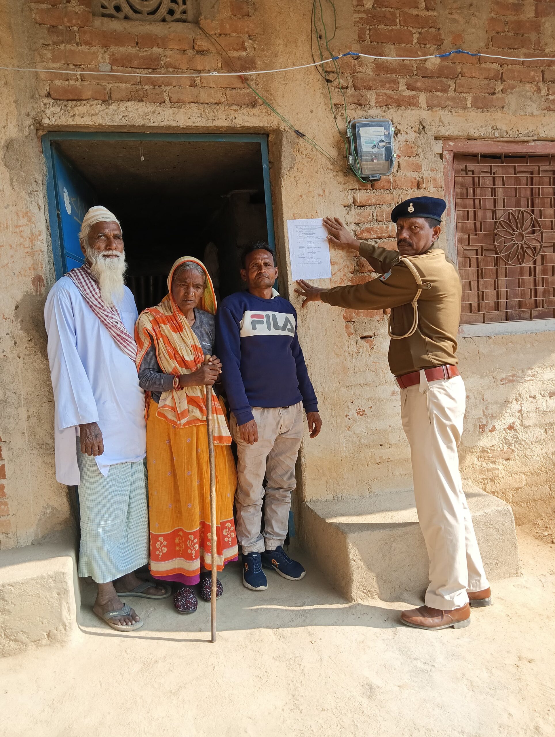 फरार अभियुक्त के घर पर पुलिस ने चिपकाया इश्तेहार